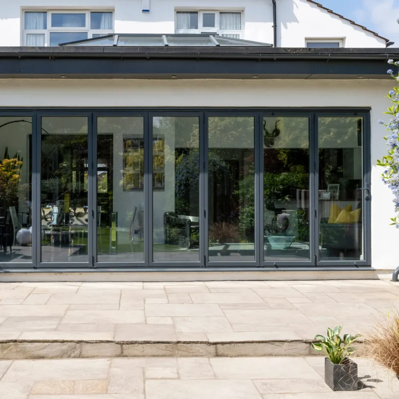 Stylish, closed, bifold doors with plants in spring, summer, revealing interior of a designer, lifestyle, kitchen diner room.
